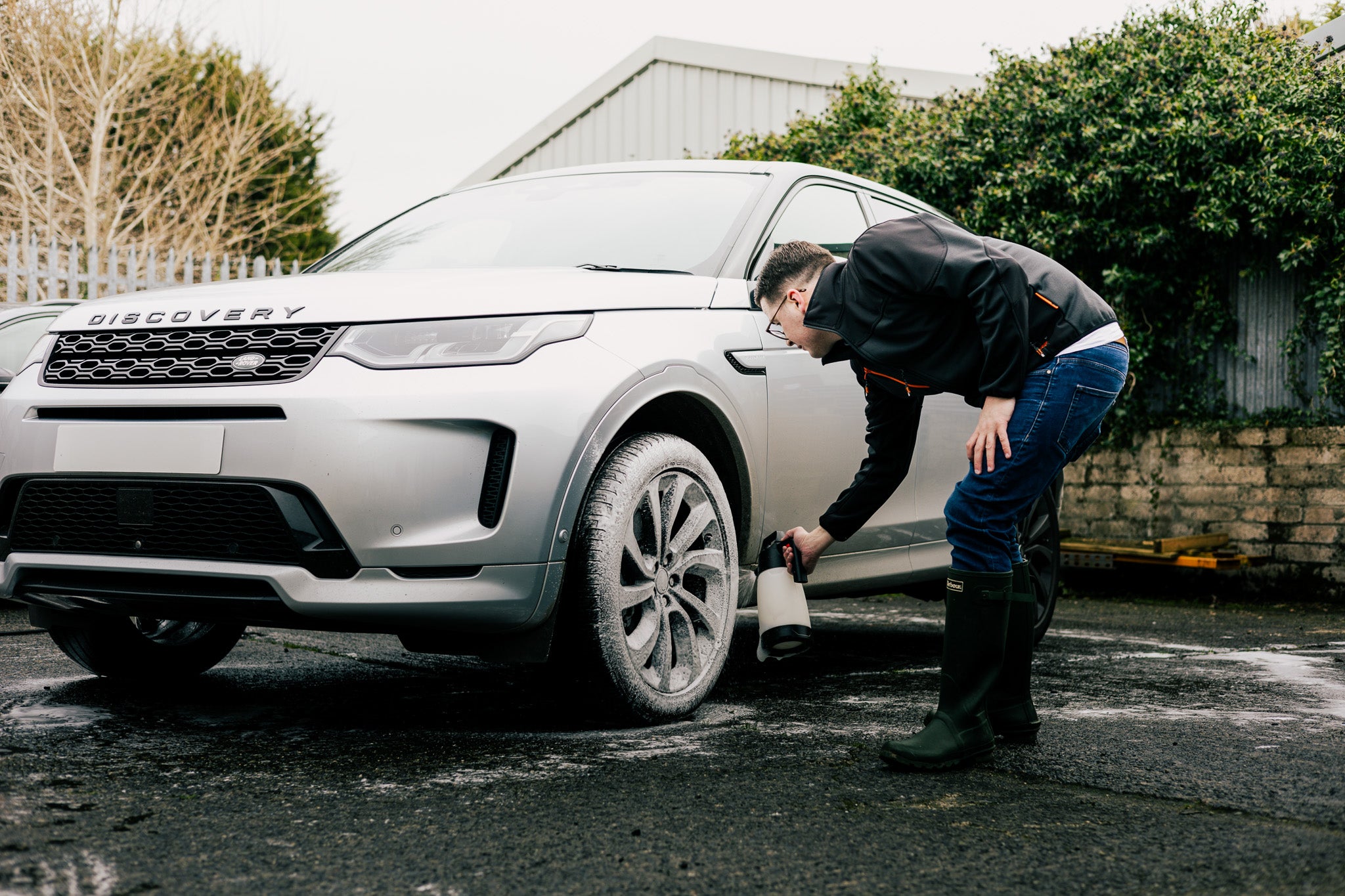 Person cleaning a tyre of a Land Rover Discovery in an outdoor setting