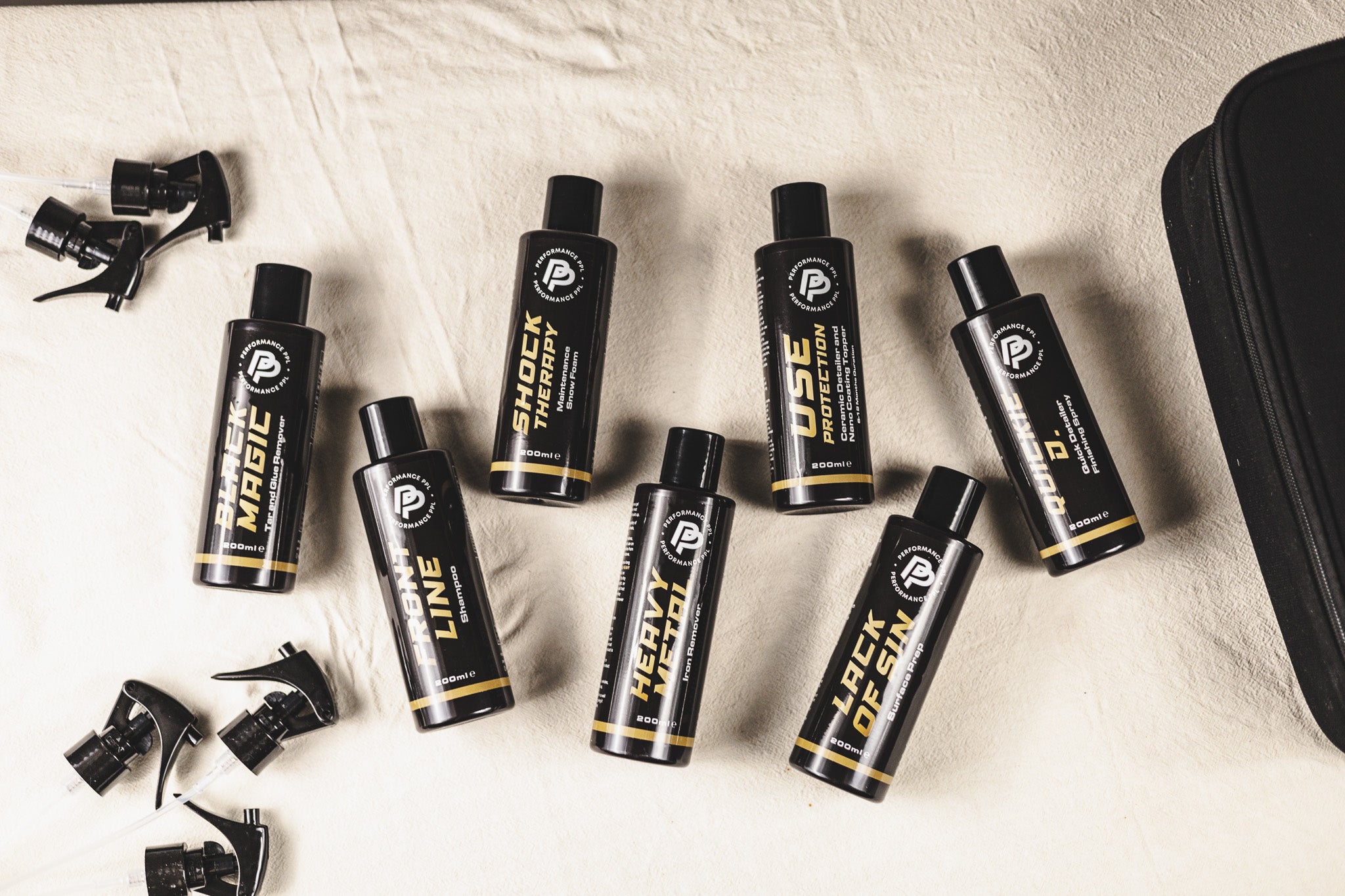 A collection of car cleaning products and ceramic coating for car labeled with names "Black Magic," "Shock Therapy," and "Use Protection," arranged as a sample car detailing kit.