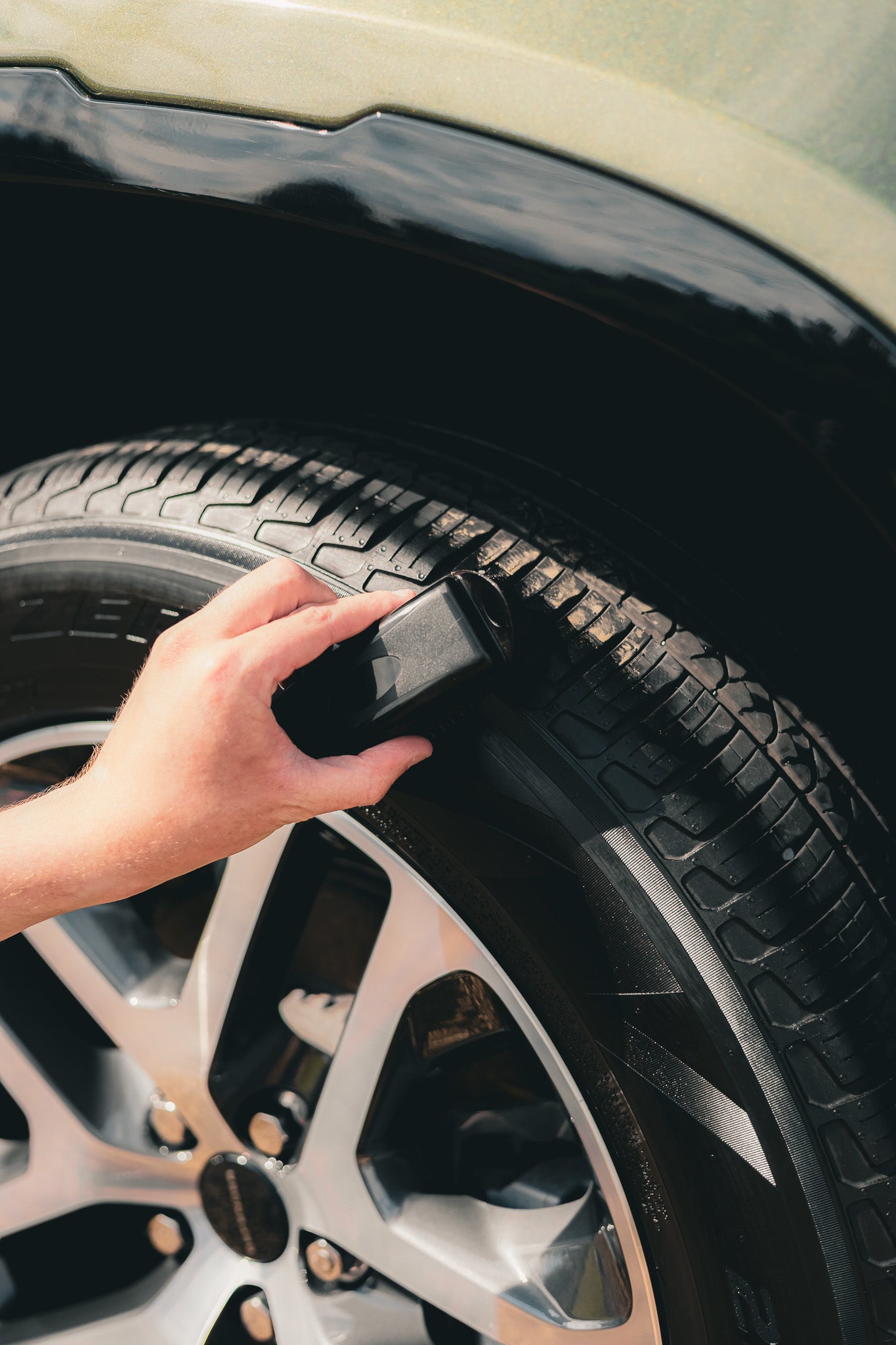 A person applying performance ppl tyre dressing on a wheel of a defender tyre .
