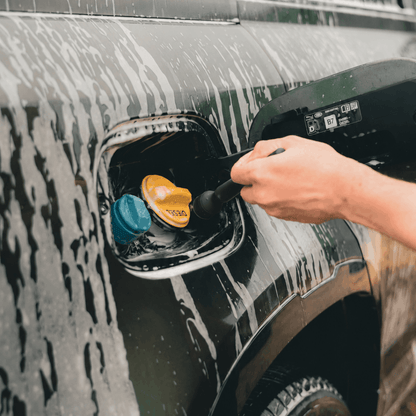 Person using an imobi detailing brush to clean the fuel cap of a black defender.