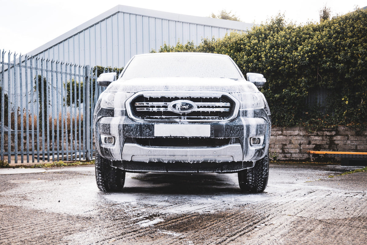 Ford Ranger covered in thick snow foam during the pre-wash stage of a professional car detailing process. High-foaming car shampoo safely loosens road grime, dirt and traffic film before contact washing to reduce swirl marks and protect the paintwork.