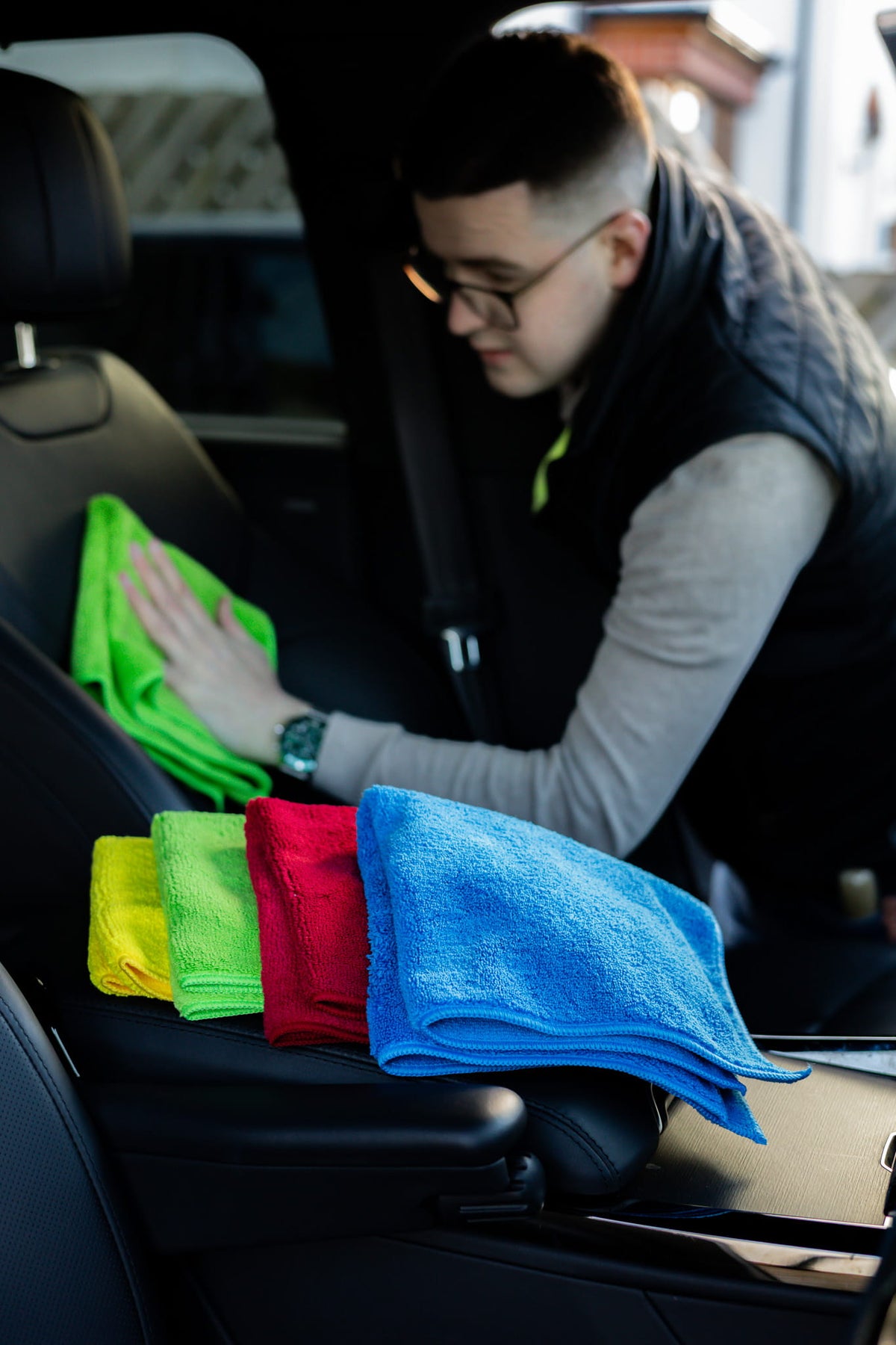 Professional detailer cleaning a car's leather interior using premium microfibre cloths during interior car valeting. High-quality car detailing cloths for dashboard cleaning, leather seat care, interior detailing and automotive cleaning.