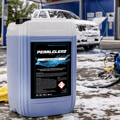 Pearlclenz Alkaline Vehicle TFR traffic film remover container at a professional car wash, with a foam-covered vehicle in the background.