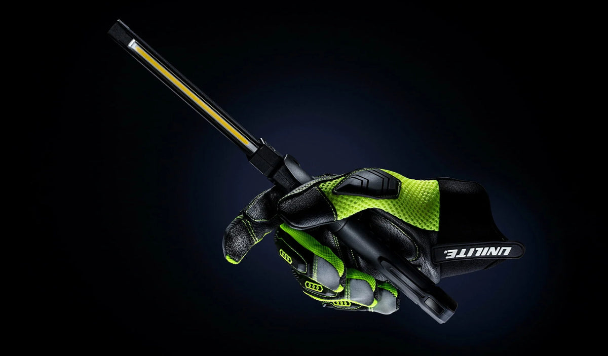 Unilite rechargeable LED inspection light held in a work glove for professional plumbing and electrical inspection.