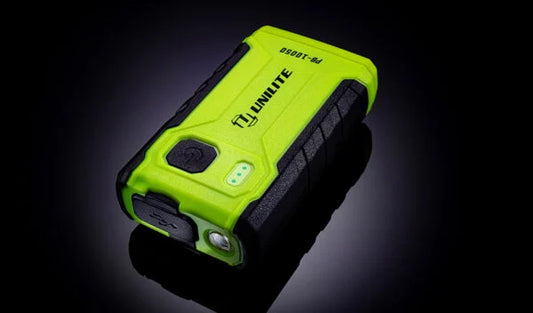 Unilite rechargeable powerbank with LED work light with high-visibility green casing, shown in wet and rugged conditions for professional detailing and workshop use.